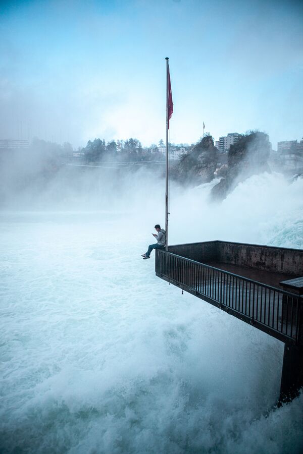 Мужчина сидит над Рейнским водопадом в Швейцарии  - Sputnik Армения