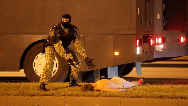 Сотрудник правоохранительных органов рядом с лежащим на земле протестующим во время столкновений после закрытия избирательных участков президентских выборов (9 августа 2020). Минск - Sputnik Армения