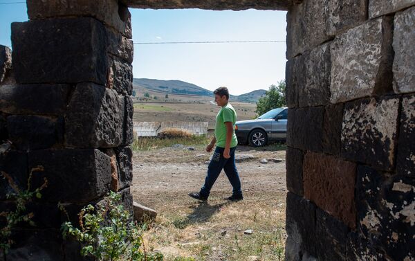 Молодой житель села Джрадзор в Ширакской области проходит мимо полуразрушенного дома - Sputnik Армения
