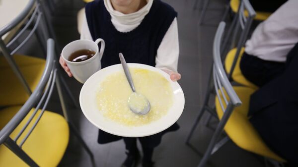 Школьница несет тарелку с кашей и чай к столу в столовой. - Sputnik Армения