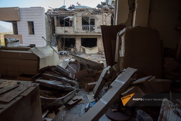 Вид на попавший под обстрел ВС Азербайджана жилой дом из окна пострадавшего мебельного магазина в Степанакерте, Карабах - Sputnik Армения
