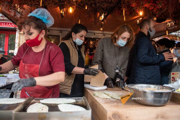 Нарине Абгарян помогает прибывшим из Карабаха женщинам продавать женгялов хац на улице Московян (6 ноября 2020). Еревaн - Sputnik Армения