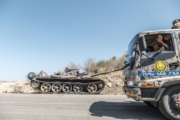 Брошенный на дороге танк и проезжающий мимо грузовик спецназа Амхара возле Хумеры, Эфиопия - Sputnik Армения