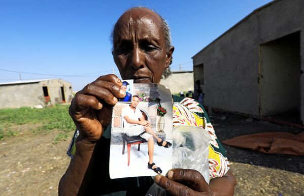 Эфиопская женщина показывает фото своих родственников - Sputnik Армения