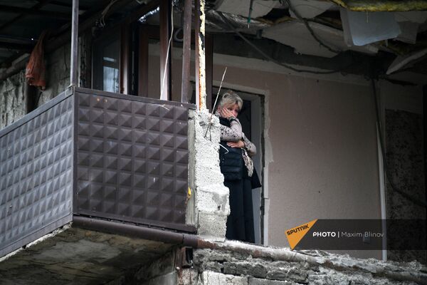 Женщина в своей квартире дома в Степанакерте, пострадавшего во время обстрела - Sputnik Армения