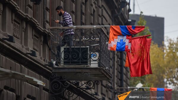 Молодой человек беседует по телефону на балконе в здании Верховного органа АРФД (3 декабря 2020). Еревaн - Sputnik Армения