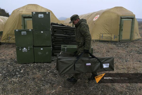 Российский военнослужащий выгружает оборудование на территории мобильного полевого госпиталя неподалеку от Степанакерта (29 ноября 2020). Карабах Российский военнослужащий выгружает оборудование на территории мобильного полевого госпиталя неподалеку от Степанакерта (29 ноября 2020). Карабах - Sputnik Армения