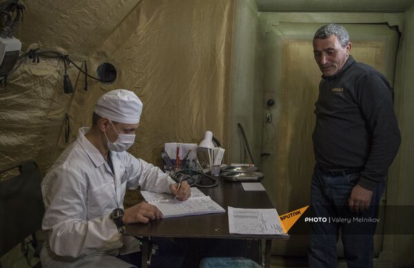Врач проводит прием пациента на базе госпиталя развернутого Министерством обороны России на территории аэропорта в Степанакерте (3 декабря 2020). Карабах Врач проводит прием пациента на базе госпиталя развернутого Министерством обороны России на территории аэропорта в Степанакерте (3 декабря 2020). Карабах - Sputnik Армения