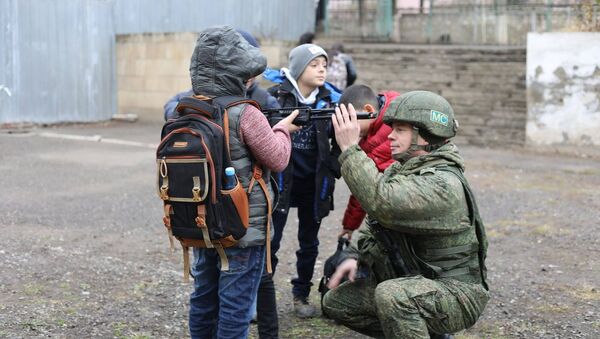 Мальчишки рассматривают оружие миротворца во дворе школы в Степанакерте - Sputnik Արմենիա