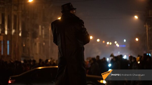 Мужчина в плаще следит за шествием оппозиции, требующих отставки правительства Армении (14 декабря 2020). Еревaн - Sputnik Армения