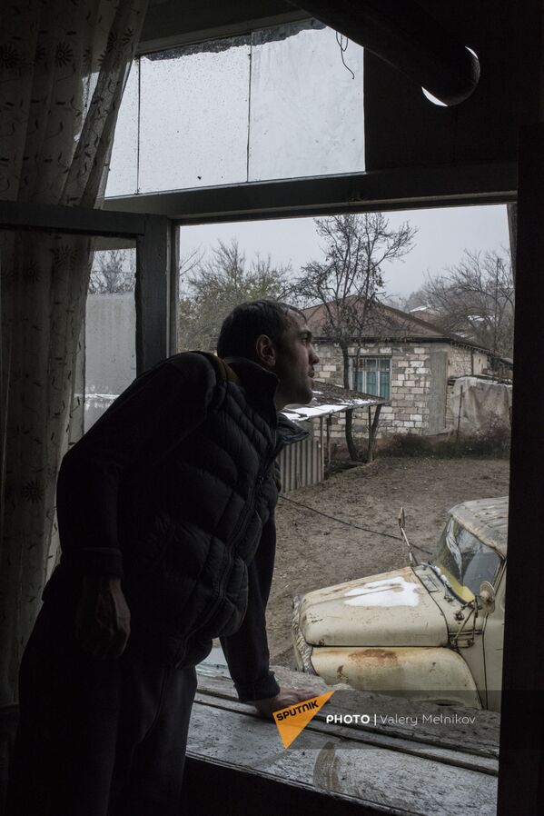 Արցախի Մարտունու շրջանի Թաղավարդ գյուղում տղամարդը նայում է իր տան պատուհանից։ - Sputnik Արմենիա
