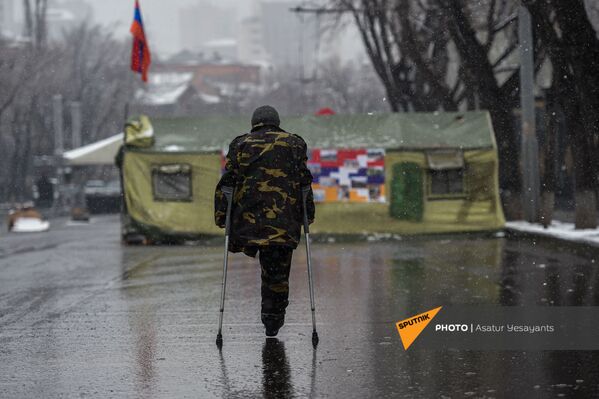 Ветеран войны с ампутированной ногой на фоне палаток, установленных на заблокированном оппозиционерами проспекте Баграмяна (1 марта 2021). Еревaн - Sputnik Армения