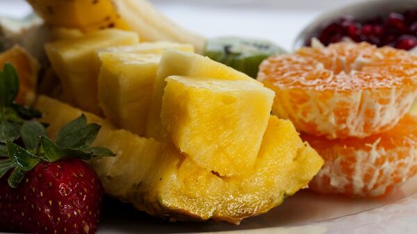 Нарезанный ломтиками свежий ананас с мандаринами и клубникой - Sputnik Армения