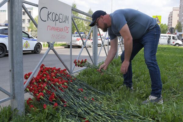 Мужчина возлагает цветы рядом с гимназией № 175 (11 мая 2021). Казань - Sputnik Армения