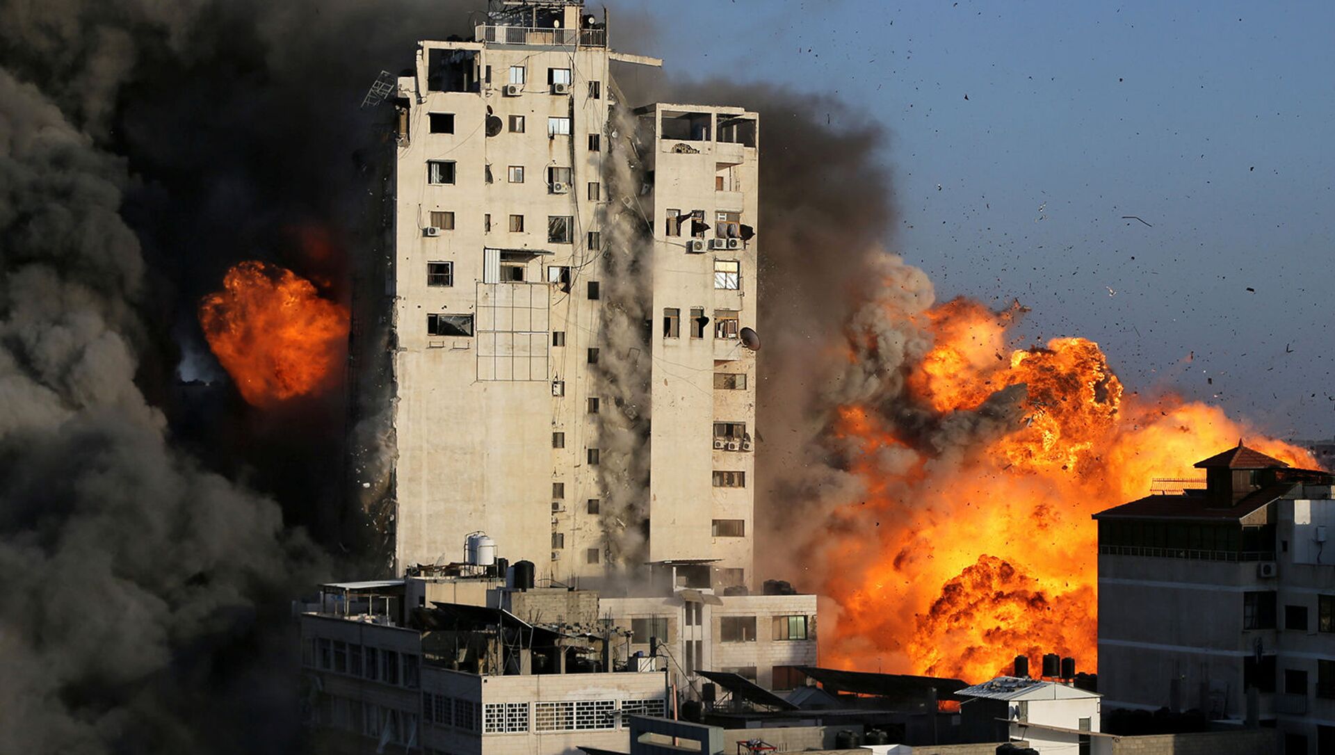 Дым и пламя поднимаются над зданием башни, разрушенным израильскими воздушными ударами на фоне вспышки израильско-палестинского конфликта в городе Газа (12 мая 2021). - Sputnik Армения, 1920, 14.05.2021