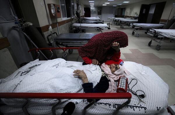 Палестинская девочка рядом со своей раненой бабушкой в больнице Аль-Шифа после израильского удара по лагерю беженцев аш-Шати (15 мая 2021). Газа  - Sputnik Армения