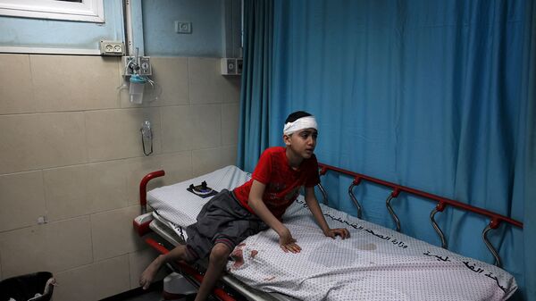 Раненый палестинский мальчик на койке в больнице Аль-Шифа после израильского удара по лагерю беженцев аш-Шати (15 мая 2021). Газа  - Sputnik Армения