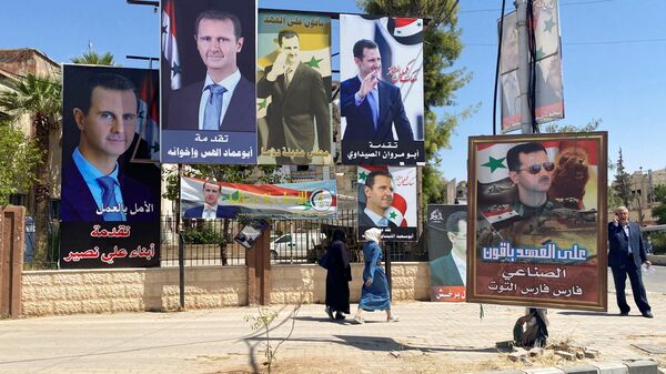 Женщины проходят возле плакатов с изображением президента Сирии Башара аль-Асада во время президентских выборов - Sputnik Армения