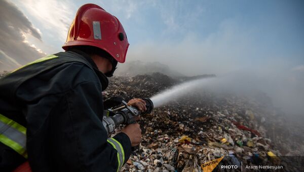 Сотрудник МЧС тушит пожар на нубарашенской мусорной свалке - Sputnik Армения