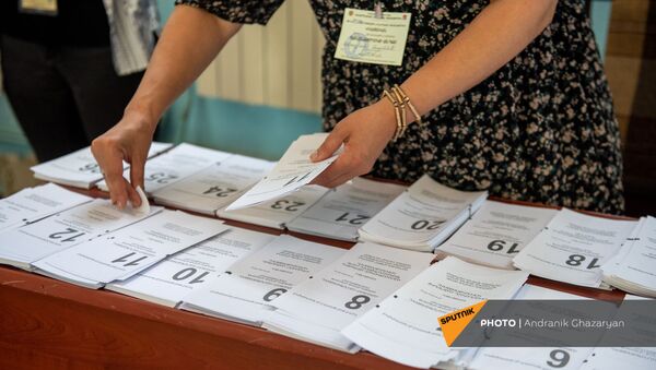 Сотрудник избирательной комиссии собирает пакет бюллетеней в избирательном участке 29/29 (20 июня 2021). Ариндж - Sputnik Армения