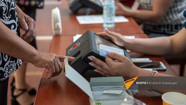 Сотрудник избирательной комиссии проверяет личность избирателя в избирательном участке 29/29 (20 июня 2021). Ариндж - Sputnik Армения
