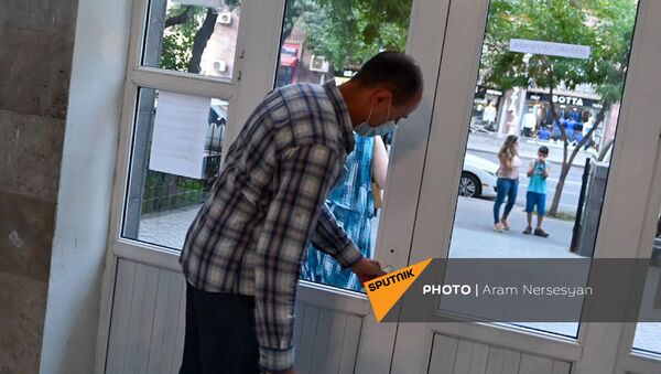 Член избирательной комиссии участка 9/26 закрывает двери участка по окончании времени голосования (20 июня 2021). Еревaн - Sputnik Արմենիա