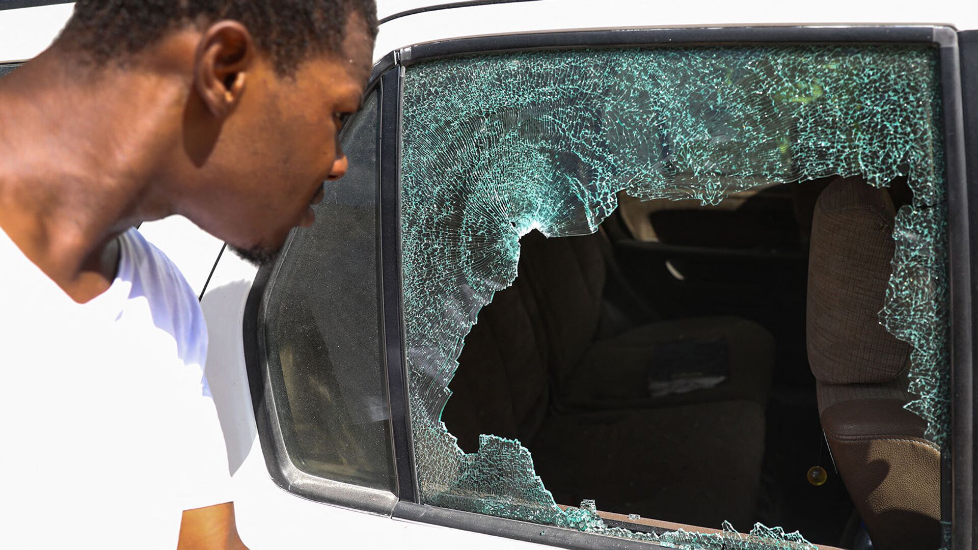 Мужчина смотрит на пулевые отверстия в машине возле президентской резиденции в Порт-о-Пренсе (7 июля 2021). Гаити - Sputnik Արմենիա, 1920, 09.07.2021