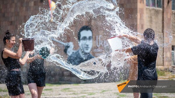 Девушки обливают друг друга водой во время Вардавара на фоне графити погибшего героя войны (11 июля 2021). Раздан - Sputnik Армения