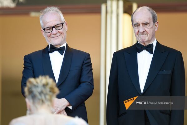 Директор и президент Каннского кинофестиваля Тьерри Фремо (слева) и Пьер Лескюр улыбаются актрисе Шэрон Стоун, поднимающейся по лестнице  (14 июля 2021). Франция - Sputnik Армения