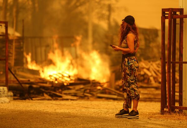 Девушка смотрит на лесной пожар близ города Манавгат, к востоку от курортного города Анталья (29 июля 2021). Турция - Sputnik Армения