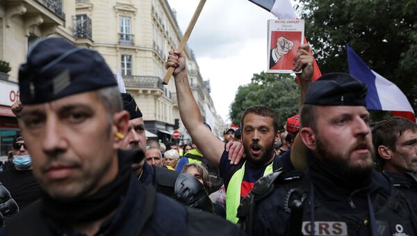 Протестующий с французским флагом и книгой Теория диктатуры во время демонстрации против пропуска COVID-19 (31 июля 2021). Париж - Sputnik Армения