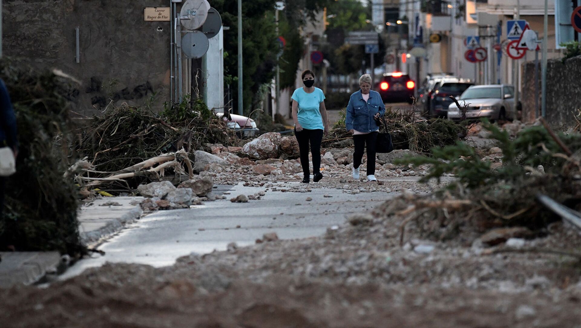Женщины идут по улице, перекрытой упавшими деревьями и камнями после наводнения, вызванного проливными дождями в Альканаре (2 сентября 2021). Испания - Sputnik Армения, 1920, 02.09.2021