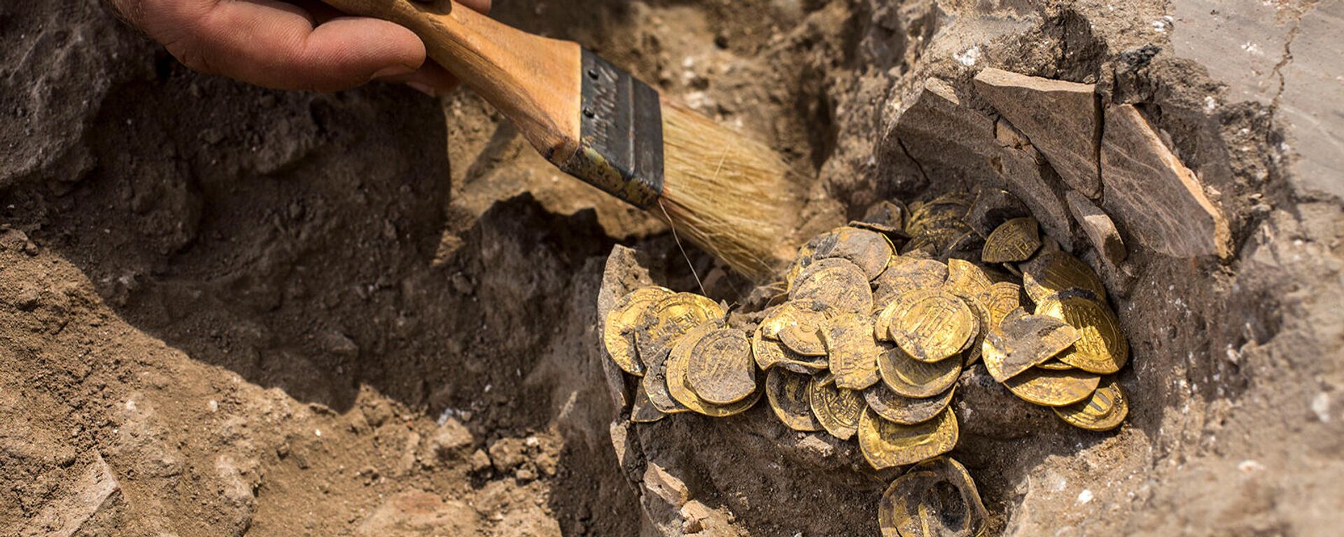 Археолог очищает обнаруженные на месте раскопок золотые монеты (18 августа 2020). Израиль - Sputnik Армения, 1920, 09.11.2021