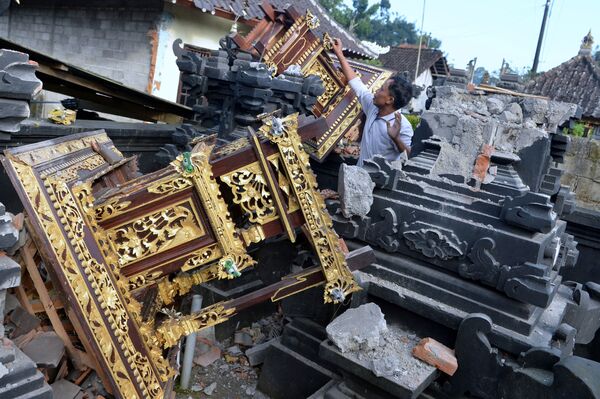 Мужчина среди поврежденных зданий храма после землетрясения силой 4,8 балла, произошедшего в Карангасеме на Бали в ночь на 16 октября 2021 года. - Sputnik Армения