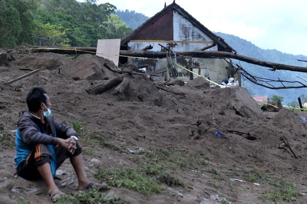 Житель сидит возле домов на месте оползня, вызванного землетрясением силой 4,8 балла в деревне Трунян в Бангли на индонезийском острове Бали. - Sputnik Армения