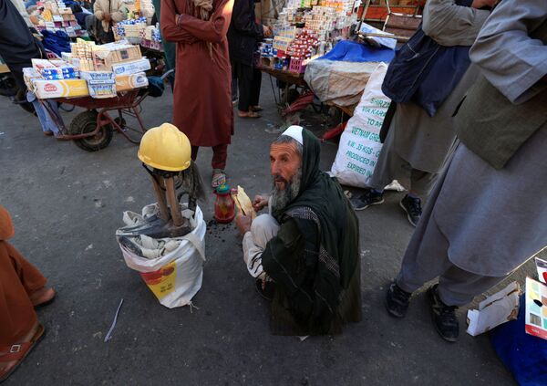 55-летний Гул Мохаммад завтракает, сидя рядом со своими инструментами в ожидании работы на рынке в Кабуле, Афганистан. - Sputnik Армения