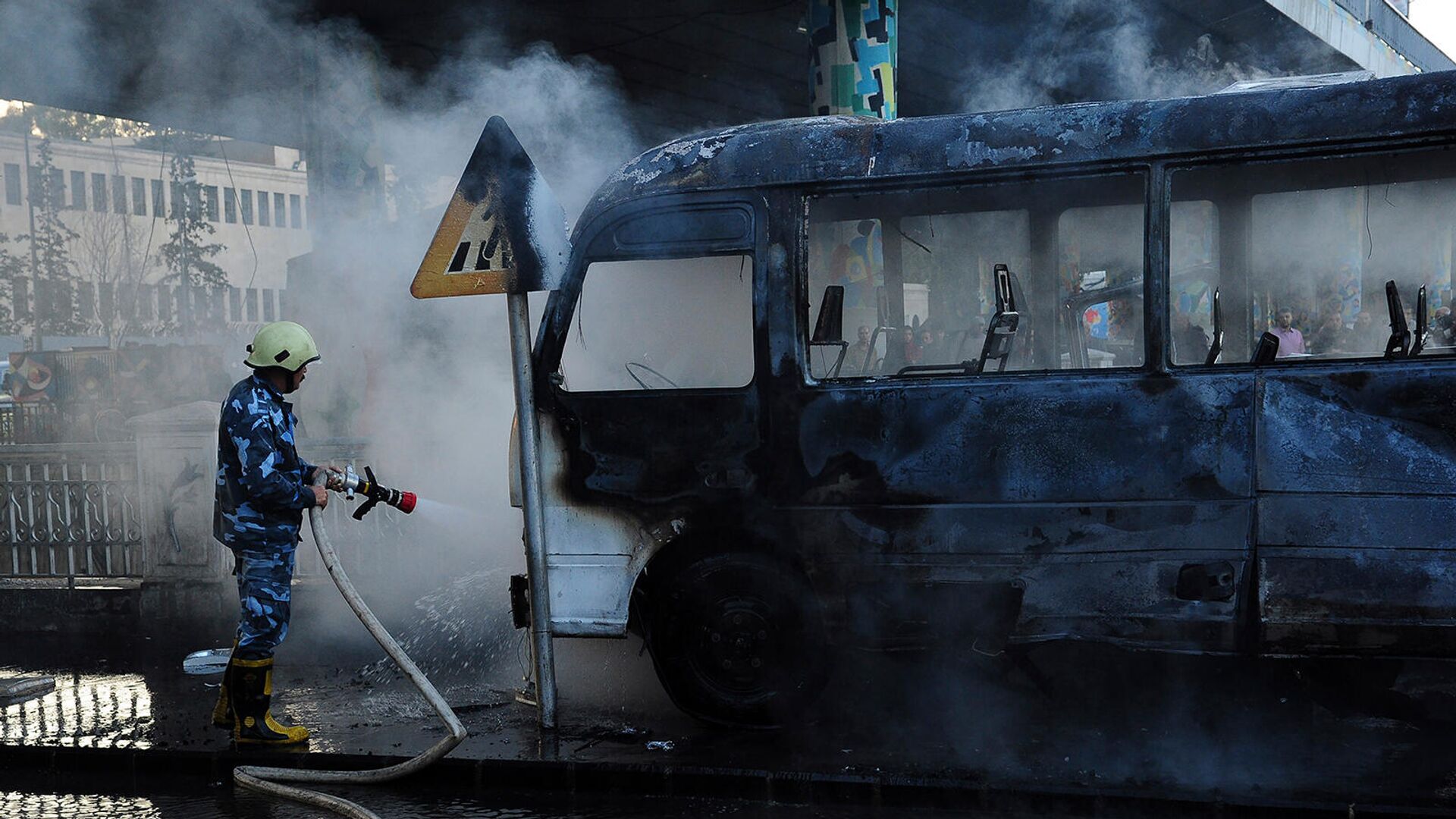 Сирийский пожарный тушит сгоревший автобус  - Sputnik Армения, 1920, 20.06.2022