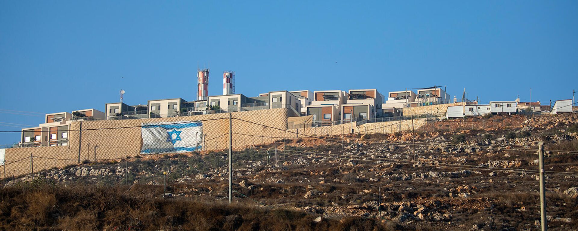 Израильский флаг на окружающей стене еврейского поселения Мигдалим на Западном берегу недалеко от палестинского города Наблус - Sputnik Армения, 1920, 29.10.2021