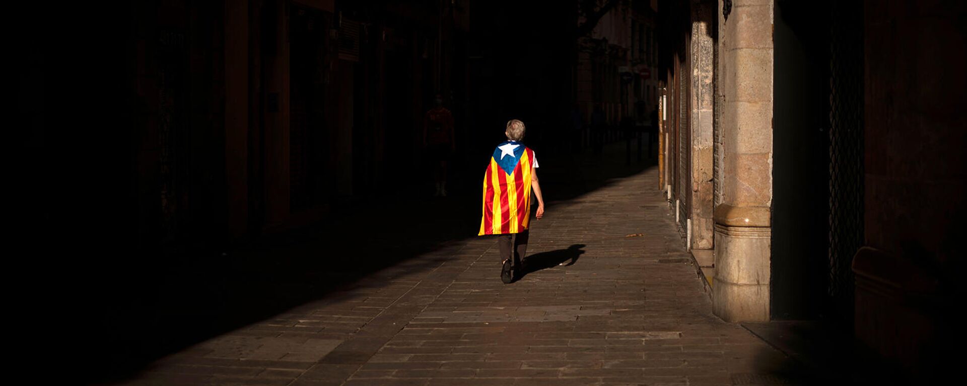 Женщина с флагом эстелады или независимости идет по пустой улице во время Национального дня Каталонии (11 сентября 2020). Барселона - Sputnik Армения, 1920, 06.11.2021