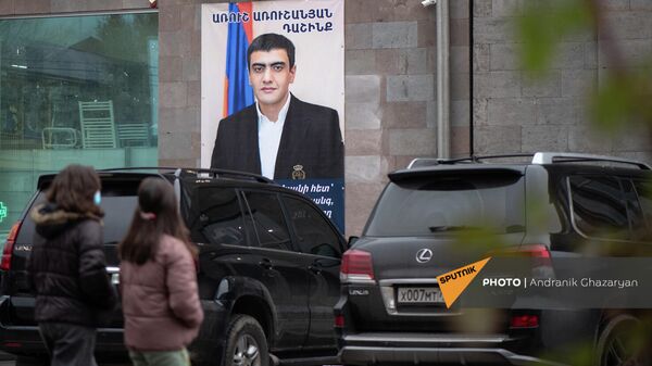 Люди проходят мимо агитационного предвыборного плаката блока Аруша Арушаняна в Горисе - Sputnik Армения