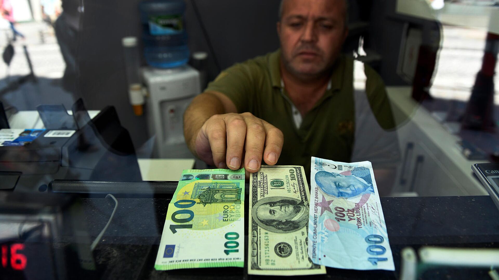 Сотрудник пункта обмена валюты с банкнотами в 100 евро, долларов США и турецких лир - Sputnik Армения, 1920, 18.05.2023