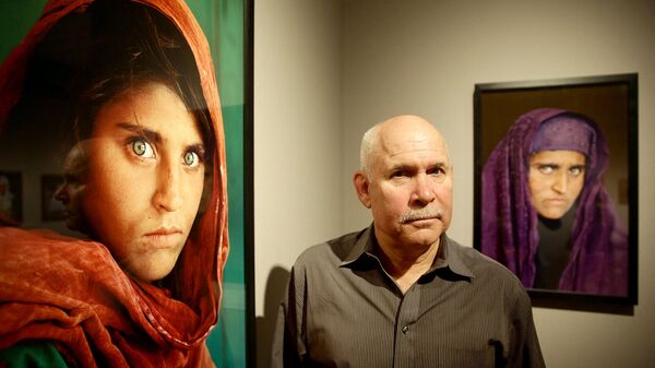 Американский фотограф Стив Маккарри рядом со своими фотографиями Афганской девушки по имени Шарбат Гула на открытии выставки его работ Переполненный жизнью (27 июня 2013). Гамбург - Sputnik Армения