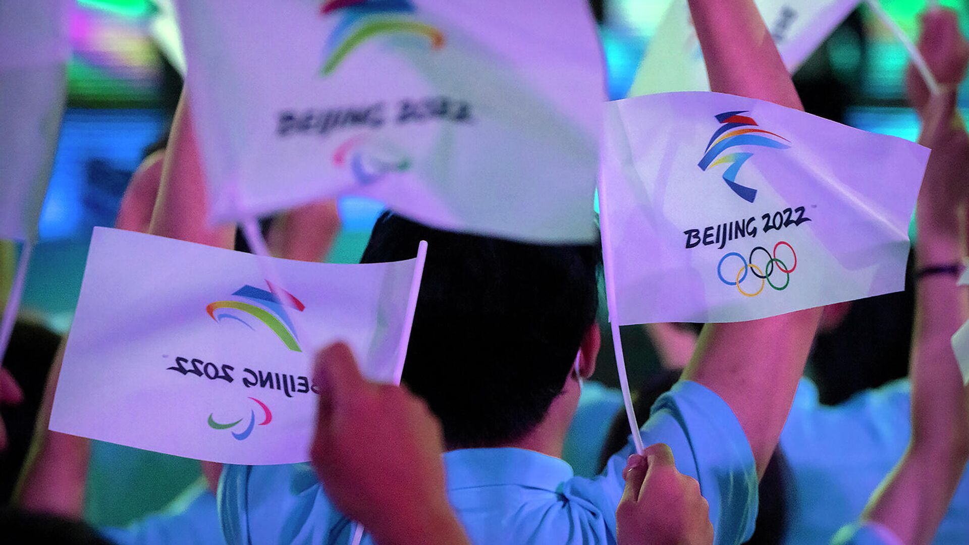 Участники размахивают флагами с логотипами зимних Олимпийских и Паралимпийских игр 2022 года в Пекине перед церемонией открытия (17 сентября 2021). Пекин - Sputnik Армения, 1920, 14.03.2022
