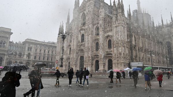 Люди идут по площади Пьяцца дель Дуомо мимо собора под снегопадом в Милане - Sputnik Армения