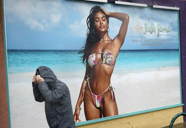 Мужчина проходит мимо магазина купальных костюмов Mission Beach в Сан-Диего. Мощный шторм обрушился на Калифорню, затрудняя движение транспорта и создавая угрозу оползней в районах, пострадавших от лесных пожаров. - Sputnik Армения