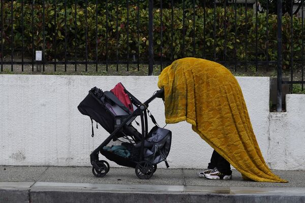 Бездомный пытается укрыться от дождя в центре Лос-Анджелеса - Sputnik Армения