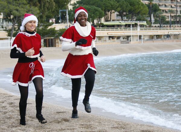 Ձմեռ պապիի զգեստներով աղջիկները վազում են Միջերկրական ծովի ափին։ - Sputnik Արմենիա