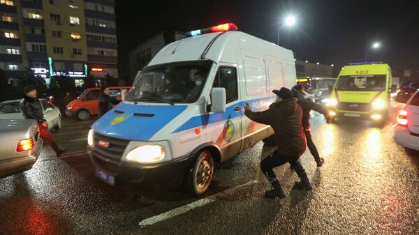 Люди нападают на полицейский микроавтобус во время акции протеста против повышения стоимости на топливо в Алматы - Sputnik Армения