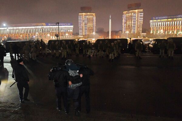 Сотруднику правоохранительных органов Казахстана помогают возле мэрии во время протестов, вызванных повышением цен на топливо - Sputnik Армения