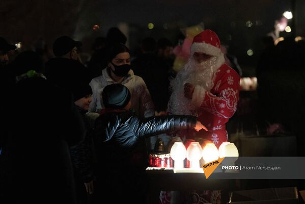 Аниматор в костюме Деда Мороза раздает лампады Чрагалуйса прихожанам церкви святой Троицы. - Sputnik Армения